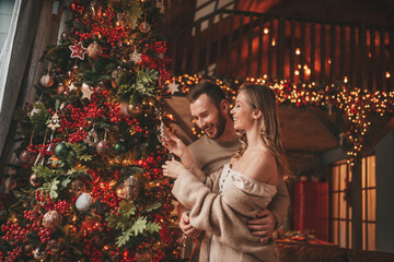 Candid authentic happy married couple spending time together at wooden lodge Xmas decorated