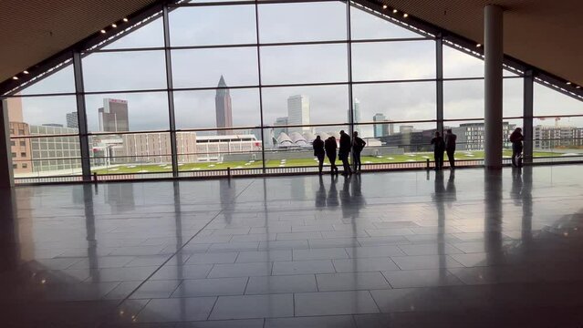 People walking in a modern building with the Frankfurt city in background.