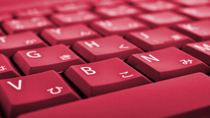 Japanese typing. Laptop keyboard closeup. Symbols on buttons of hiragana. Bright red tinted...