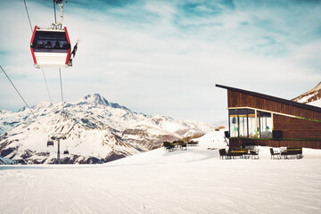 White red closed ski lift cabin with skiers and white dramatic snowy mountains background. Ski...