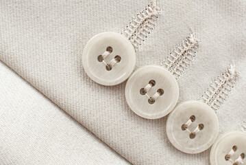 Buttons on the sleeve of a white men's jacket. White button closeup