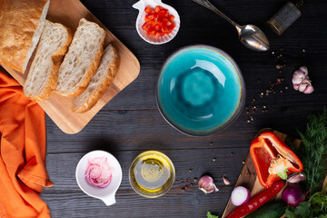 fresh ciabatta bread  with blue bowl and ingredients served at dark wooden table. meditarranean cuisine. flat lay