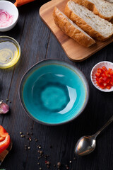 fresh ciabatta bread  with blue bowl and ingredients served at dark wooden table. meditarranean cuisine. flat lay