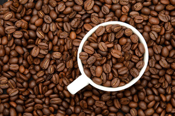 Coffee poured into a cup and coffee beans scattered around