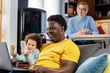 Father spends time with a cute daughter watching a laptop computer with her. Multicultural family. Educational apps for small kids.