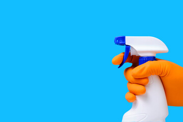 Sprayer for cleaning windows and plumbing in hand with glove on blue background.