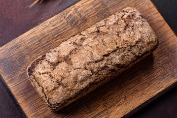 A loaf of brown bread with grains of cereals on a wooden cutting board