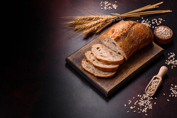 A loaf of brown bread with grains of cereals on a wooden cutting board