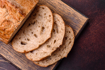 A loaf of brown bread with grains of cereals on a wooden cutting board