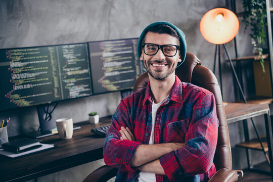 Photo of confident cheerful programmer wear spectacles arms folded smiling indoors workplace workshop home