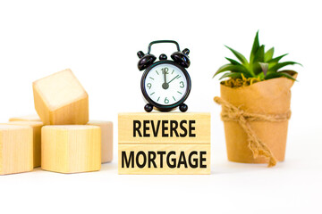 Reverse mortgage symbol. Concept words Reverse mortgage on wooden blocks. Beautiful white table white background. Black alarm clock. Business and reverse mortgage concept. Copy space.