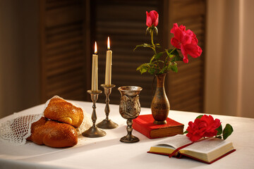 Challah bread covered with a special napkin, shabbat wine,  candles on table. Traditional Jewish Shabbat ritual. Shabbat Shalom.