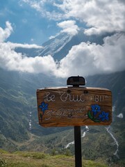 Wooden sign over green mountains in Haute Savoie in France with blue gray sky