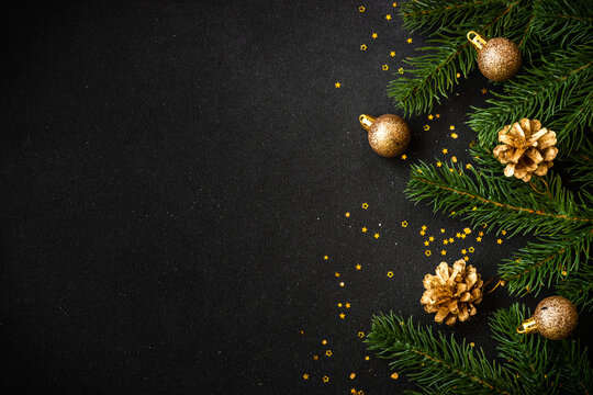 Christmas flat lay background with golden holiday decorations on black. Top view with copy space.