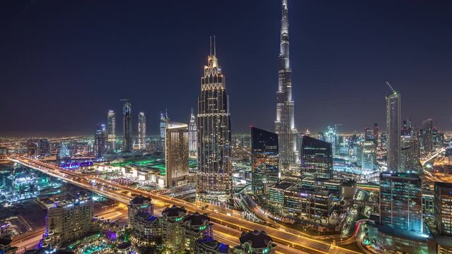 Panorama of Dubai downtown skyline day to night transition timelapse with tallest building and Sheikh Zayed road traffic, UAE. Aerial view from rooftop of skyscraper with modern towers after sunset