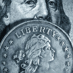 Close up one hundred US Dollar and coin with description: Liberty. Selective focus on coin...