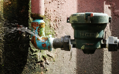Water leaks from a long-used blue plumbing pipe.	