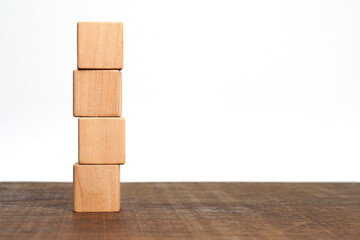 Four empty wooden cube blocks stack on the table on white background with copy space. Pile of wood...