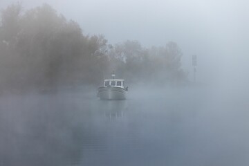 Picturesque view of a ship on a Murten Lake on a foggy autumnal morning