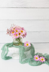 Small Vase of Pink Daisy Chrysanthemums with Sage Green Material on Cement Counter with Shiplap Background