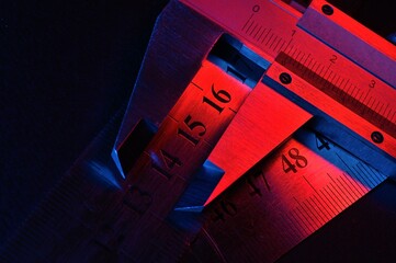 caliper and metal rulers illuminated in red and blue. close-up