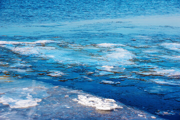 Ice surface of the river. The texture of fragments of ice and water during the icing period. Winter background.