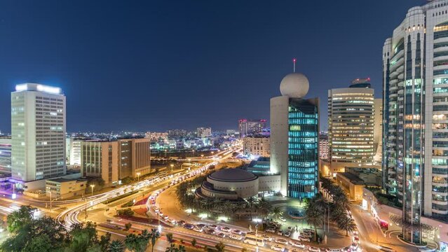 Dubai Creek area surrounded by modern buildings and busy traffic street day to night transition timelapse. Aerial top view from above after sunset with illuminated skyscrapers