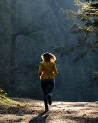 Woman makes a light jog through the misty forest in the morning, dawn and foggy morning in the woods.