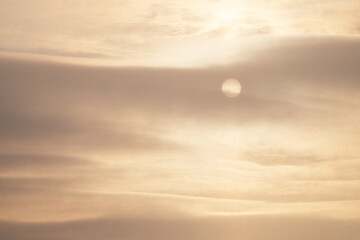 A cold winter sky with a pale disk of the sun in the gap between the snow clouds. Natural...