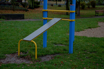 Fototapeta na wymiar outdoor sports field. exercise equipment with gymnastic rings to strengthen the arms. bench for training the abdominal and back tendons and attachments