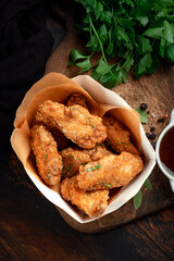 Fried chicken wings with crispy crust on box package for delivery. Grilled chicken wings served with bbq sauce, rustic style, top view