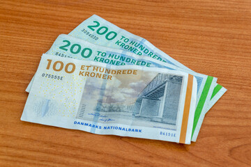 Danish krone (DKK) banknotes on wooden table.