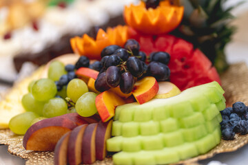 Close-up of a plate full of grapes, peaches, apples, pears, oranges, blueberries and other whole or sliced fruits. Healthy lifestyle, fruit-based diet. Narrow depth of field.