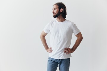 Fototapeta premium Portrait of a man with a black thick beard and long hair in a white T-shirt on a white isolated background