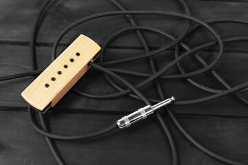 Acoustic guitar pickup on wooden background
