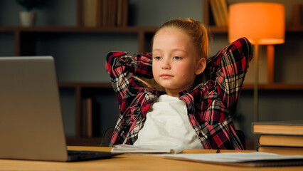 Little preschooler pupil girl watch tutor lesson by video call e-learning take break during homework education put hands behind head feel relaxed stress-free at home no stress comfort living concept