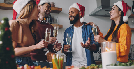 Beautiful young people talking and smiling while enjoying Christmas dinner at home