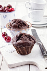Traditional American chocolate cherry muffin served as close-up on a rustic board
