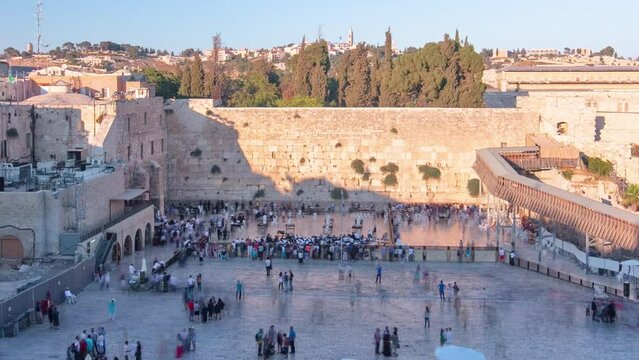 The Temple Mount in Jerusalem, including the Western Wall and the golden Dome of the Rock during Sunset timelapse. Shadow covering the wall. Many people at shabbat