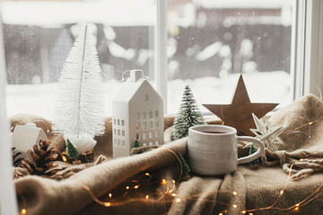 Christmas still life, winter hygge home. Warm cup of tea, christmas decorations, lights, little...