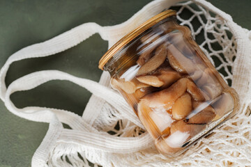 Jar of pickled mushrooms in a mesh bag. Zero waste concept with canned mushrooms and string bag....