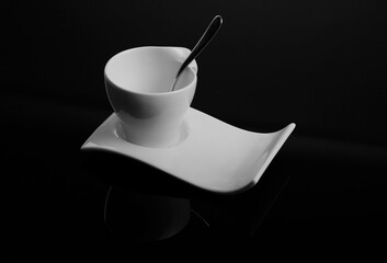 white cup on isolated black background, biała filiżanka na falistym spodku, porcelanowa filiżanka na czarnym tle, biała filiżanka, filiżanka z łayżeczką, falisty spodek, czerń i biel, czarne tło