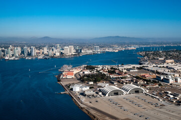 Aerial view of North Island Naval Air Base on Coronado and downtown San Diego California while flying over the bay with boats on the water and mountains in the background during daylight - obrazy, fototapety, plakaty