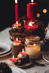 Rustic table decor for Christmas or New Year family dinner. Centrepiece with red candle, dry orange, cone, cinnamon, anise. Zero waste eco-friendly home. Cozy atmosphere, dark background. Close up