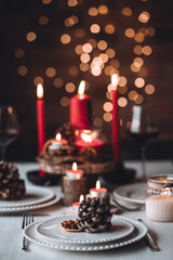 Rustic table decor for Christmas or New Year family dinner. Centrepiece with red candle, dry orange, cone, cinnamon, anise. Zero waste eco-friendly home. Cozy atmosphere, dark background. Close up