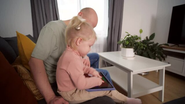 A child with cochlear implants plays with a tablet computer with his father. Deafness and medical technology concept