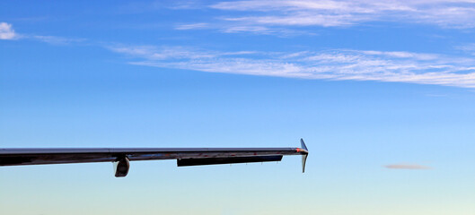 The wing end of a passenger plane under blue skies
