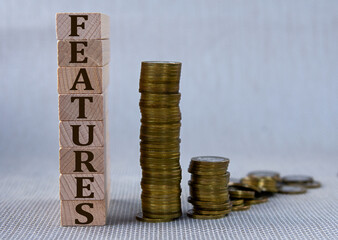 FEATURES - word on wooden cubes on the background of stacks of coins