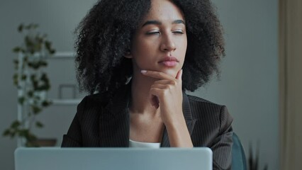 Thoughtful young businesswoman african american woman girl freelancer worker looking at laptop screen work on computer in office think new business idea check email shopping online distance chatting - Powered by Adobe