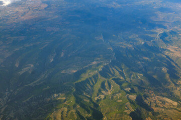 Fototapeta na wymiar White wind mills in a row on a top of a mountain green landscape in Spain, seen from an airplane